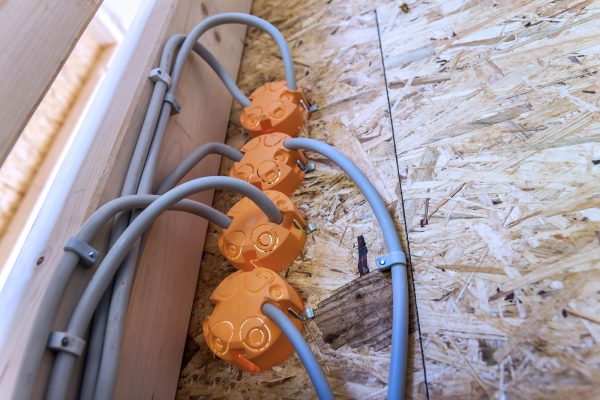 New electrical installation, socket plastic boxes and electrical cables on the wall, renovation concept. Electrical wiring installation.